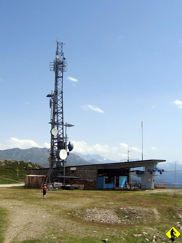 IMG_3821a.jpg - Zwycięstwo. Wieje jak diabli. Jakieś 100m przed szczytem nie dało się już jechać. Nawet prowadząc zwiewało Agnieszce jej lżejszy rower. Szkoda, że tak nas lokalny wiatr traktuje, bo chciałem tam posiedzieć na ławce i patrzeć na góry do wieczora… Pozostaje zjechać na dół... co zajmie nam ok. 30 -40 min z kilkoma przerwami. Jedyne co mnie hamowało to to, że nie było widać co jest za zakrętami, a samochody wcale nie były tu obce.
